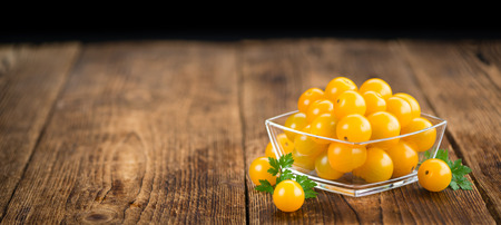 Yellow Tomatoes as high detailed close-up shot on a vintage wooden table; selective focusの写真素材