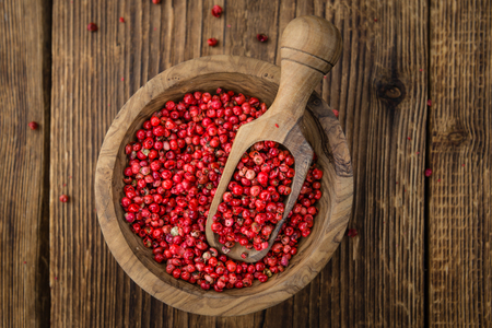 Pink Peppercorns on an old wooden table as detailed close-up shot; selective focusの写真素材