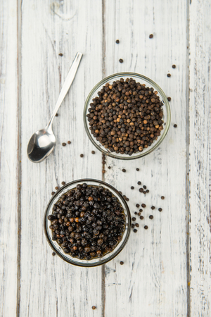Preserved black Peppercorns on wooden background; selective focus; close-up shotの写真素材