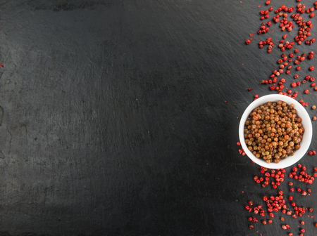 Some Pink Peppercorns (preserved) on a slate slab as detailed close-up shot; selective focusの写真素材