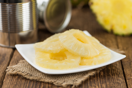 Preserved Pineapple Rings on an old wooden table as detailed close-up shot; selective focusの写真素材
