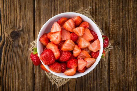 Sliced Strawberries on rustic wooden background as close-up shotの写真素材