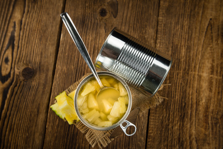 Chopped Pineapple (preserved) as high detailed close-up shot on a vintage wooden table; selective focusの写真素材