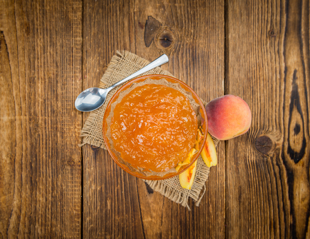Peach Jam on an old wooden table as detailed close-up shot; selective focusの写真素材