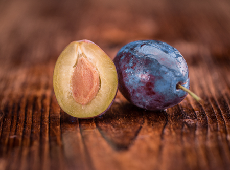 Plums as high detailed close-up shot on a vintage wooden table; selective focusの写真素材