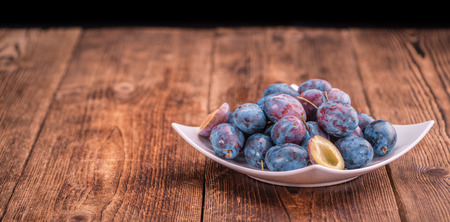 Plums on an old wooden table as detailed close-up shot; selective focusの写真素材