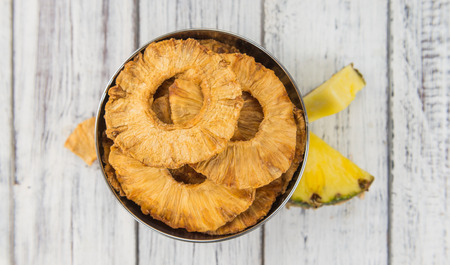 Pineapple rings (dried) on an old wooden table as detailed close-up shot; selective focusの写真素材
