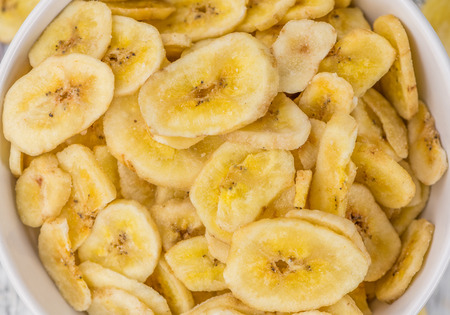 Fresh made Dried Banana Chips on an old and rustic wooden table; selective focus; close-up shotの写真素材