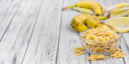 Homemade Dried Banana Chips on an wooden table as detailed close-up shot; selective focusの写真素材