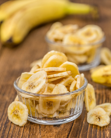 Homemade Dried Banana Chips on an wooden table as detailed close-up shot; selective focusの写真素材
