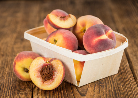 Peaches on an old wooden table as detailed close-up shot; selective focusの写真素材