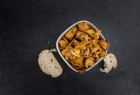 Portion of Fried Chanterelles on a rustic slate slab, selective focus, close-up shotの写真素材