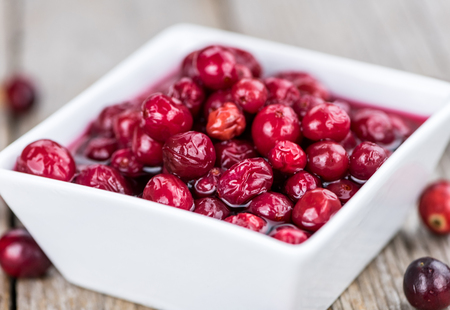 Old wooden table with fresh Preserved Cranberries (close-up shot; selective focus)の写真素材