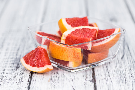 Portion of sliced Grapefruits on an old wooden table (selective focus; close-up shot)