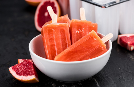 Vintage slate slab with some freshly made Grapefruit Popsicles (selective focus; close-up shot)