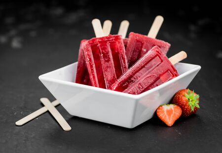 Strawberry Popsicles (close-up shot; selective focus) on a rustic backgroundの写真素材
