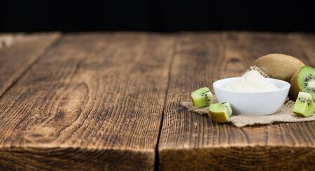 Bowl with fresh made Kiwi powder (close-up shot; selective focus) on an old wooden tableの写真素材