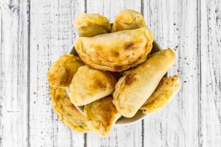 Portion of healthy Empanadas on an old wooden table (selective focus; close-up shot)