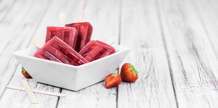 Old wooden table with homemade Strawberry ice creams (close-up shot; selective focus)の写真素材
