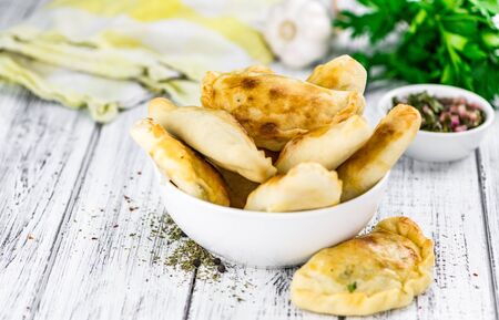 Portion of healthy Empanadas on an old wooden table (selective focus; close-up shot)
