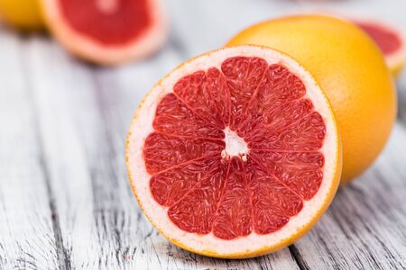 Portion of sliced Grapefruits on an old wooden table (selective focus; close-up shot)の写真素材