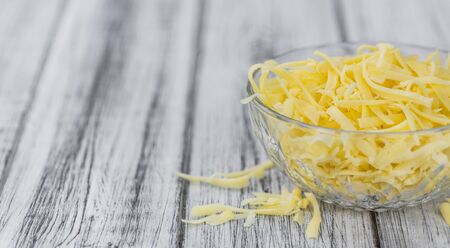 Old wooden table with grated Cheese (close-up shot)