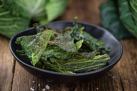 Healthy Savoy Chips on a wooden table as detailed close-up shot (selective focus)の写真素材
