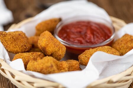 Vintage wooden table with fresh made Chicken Nuggets (close-up shot; selective focus)の写真素材