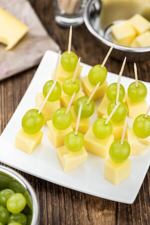 Vintage wooden table with Cheese blocks and grapes as detailed close-up shot (partyfood)の写真素材