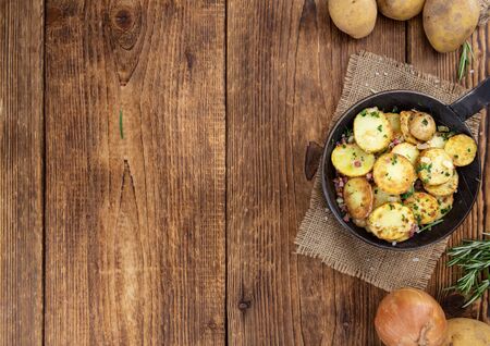 Fried Potatoes with Onions ond ham on a wooden table (selective focus)の写真素材