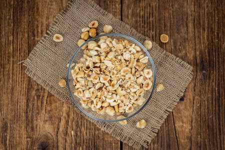 Portion of freshly chopped Hazelnuts on an old wooden table as detailed close up shot (selective...