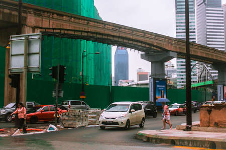 A white car making a turn in a rainy main road, right before a pedestrian crosses the roadの写真素材