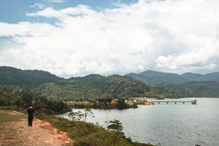 A guy walking in the vast greenery and rolling clouds in and around a dam at Kuala Kubu Baru, north...