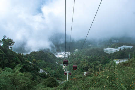 A cable car passing through the hill range in Genting Highland on a cold and chilly day with fog clouds hitting the cablesのeditorial素材