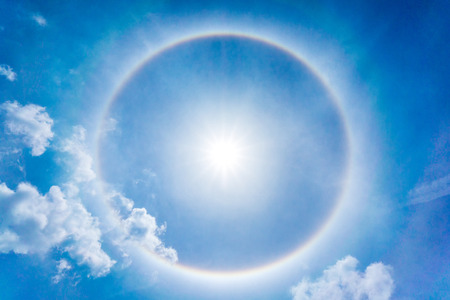 The Sun halo on the blue sky and clouds at noonの写真素材
