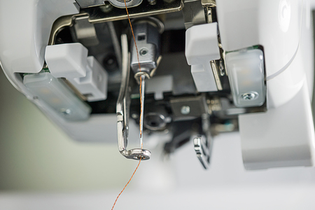 Close up look inside embroidery machines parts are as follows : holder needle, presser foot