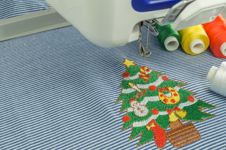 Background of close up embroidery machines workspace and Christmas tree cartoon style on blue fabric colorful threadの写真素材