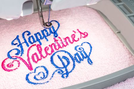 The Embroidery machine, close up image, embroidring text on pink towel in the hoopの写真素材