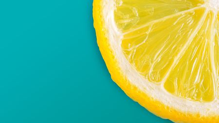 The half slice of the fresh lemon on cyan pastal color background, close up, flat lay, summer concept pictureの写真素材