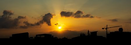 Panorama silhouette city scape and sun shining on the sky with cloud beautiful sunrise or sunset sceneの写真素材