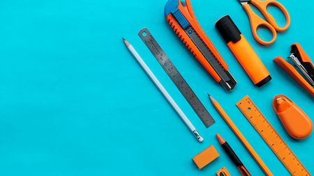Group of orange stationery on blue color paper, flat lay picture.