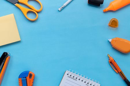 Flat lay picture of orange stationery and office supplies on blue color paper background. close up