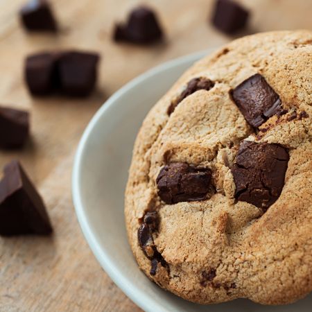 Close up picture of chocolate cookies in white plate and  pieces of chocolate bar on wood tableの写真素材