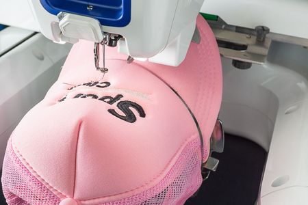 Embroidered pink cap on the hoop of white embroidery machine, close up imageの写真素材