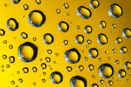 Macro picture of waterdrops on glass surface ,Lemon fruit in bubbles , texture yellow backgroundの写真素材