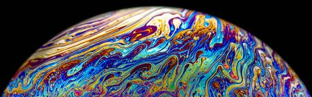 Macro picture of half soap bubble psychedelic color on black background look like planet have liquid surface in deep spaceの写真素材