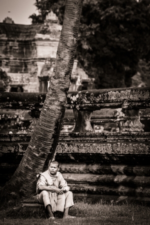 SIEM REAP, CAMBODIA - CIRCA JUNE 2012: Unidentified buddhist monk sitting on the edge of the reflection pool circa June 2012 in Angkor Wat, Cambodia The monastery is still use as part of worship sacred place.のeditorial素材
