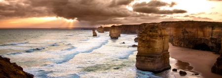 Golden sunset at 12 Apostles rock formation in Victoria, Australia  Dusk sun setting behind the backlit apostles with sea fog rolling in to the cliff face の写真素材