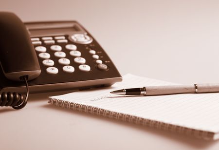business table with telephone, notepad and penの写真素材