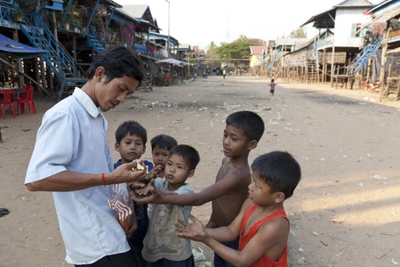  A man is giving candies to a group of children, floating village, Siemreap, Cambodia.のeditorial素材